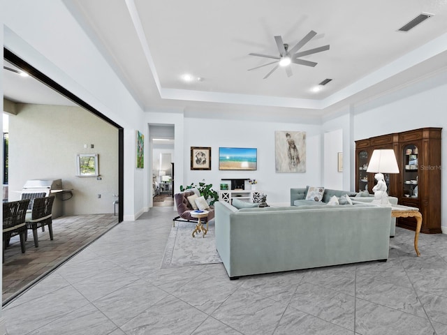 living room featuring ceiling fan and a raised ceiling