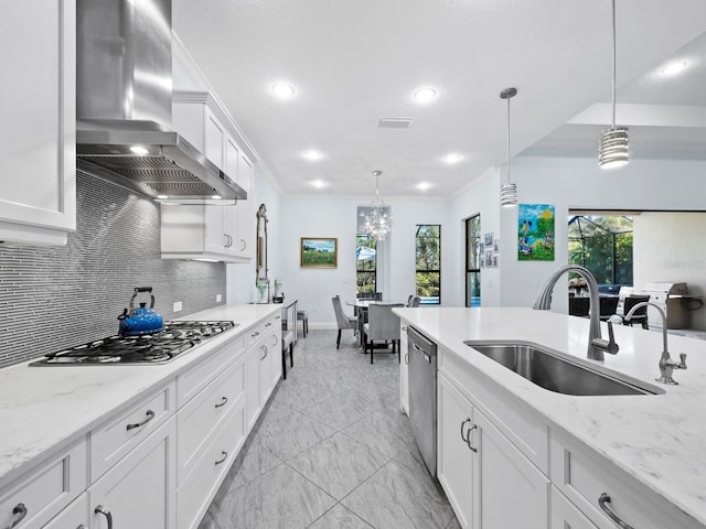 kitchen with white cabinets, decorative light fixtures, stainless steel appliances, and wall chimney range hood