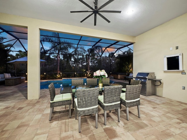 patio terrace at dusk featuring glass enclosure, area for grilling, and grilling area