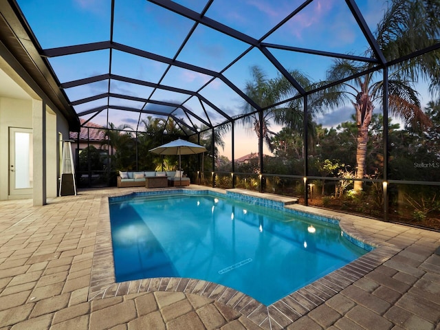 pool at dusk with glass enclosure, an outdoor hangout area, and a patio