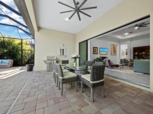 view of patio featuring glass enclosure, area for grilling, and ceiling fan