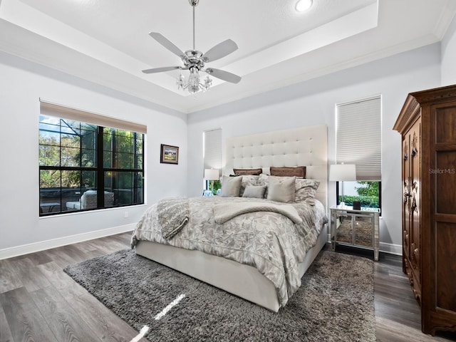 bedroom featuring a raised ceiling, ceiling fan, dark hardwood / wood-style flooring, and crown molding