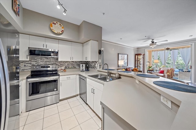 kitchen featuring appliances with stainless steel finishes, ornamental molding, sink, light tile patterned floors, and white cabinetry