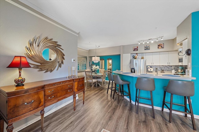 kitchen featuring stainless steel refrigerator with ice dispenser, dark hardwood / wood-style flooring, tasteful backsplash, crown molding, and white cabinets