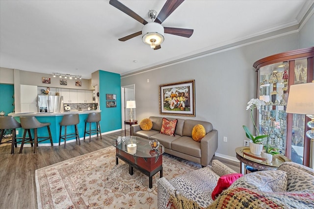 living room with ceiling fan, dark wood-type flooring, track lighting, and ornamental molding