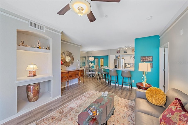 living room featuring hardwood / wood-style floors, ceiling fan, and crown molding