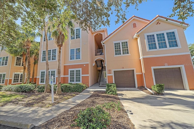 4106 Central Sarasota Pkwy Unit 1026, Sarasota, FL 34238 - view of property with concrete driveway, stucco siding, stairs, and a garage