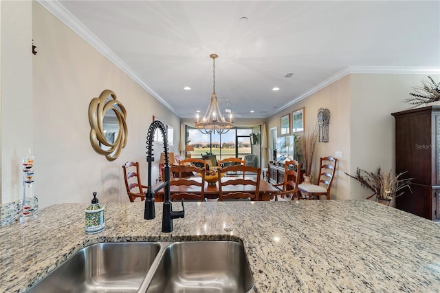 kitchen with light stone countertops, an inviting chandelier, crown molding, and sink