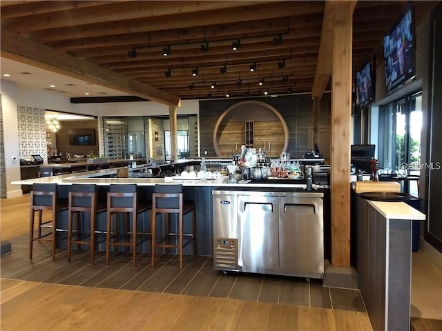 bar featuring hardwood / wood-style flooring, beam ceiling, rail lighting, and tasteful backsplash