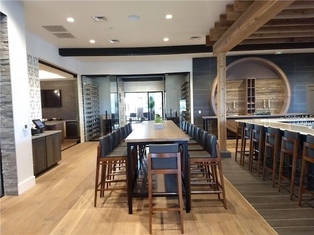 dining area featuring beamed ceiling and light hardwood / wood-style floors