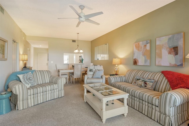 carpeted living room featuring ceiling fan with notable chandelier