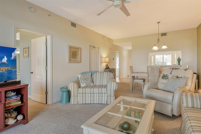 carpeted living room with ceiling fan with notable chandelier