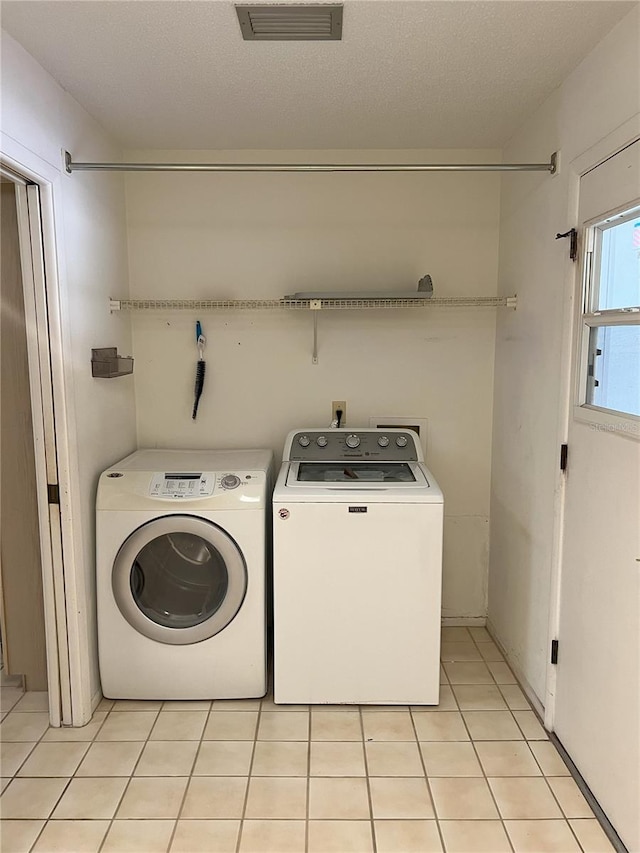 clothes washing area featuring light tile patterned flooring, a textured ceiling, and independent washer and dryer