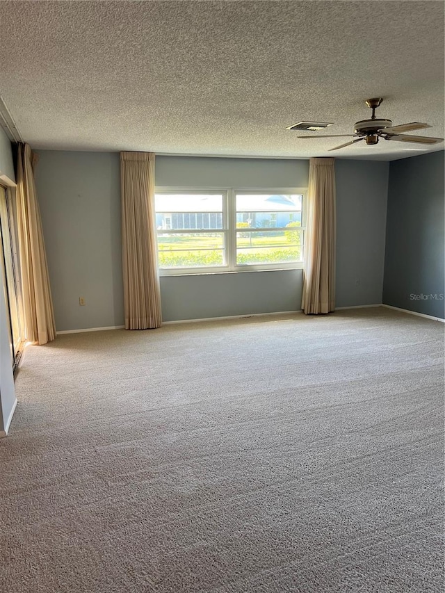 unfurnished room featuring ceiling fan, light colored carpet, and a textured ceiling