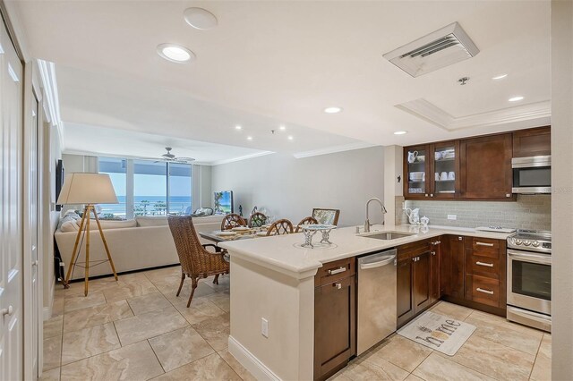 kitchen with ceiling fan, sink, stainless steel appliances, kitchen peninsula, and decorative backsplash