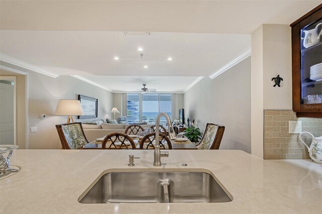 kitchen with tasteful backsplash, ceiling fan, sink, and ornamental molding