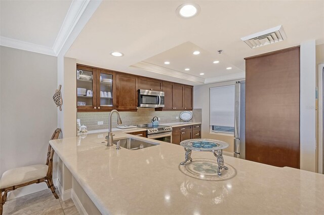 kitchen with a kitchen breakfast bar, sink, decorative backsplash, kitchen peninsula, and stainless steel appliances