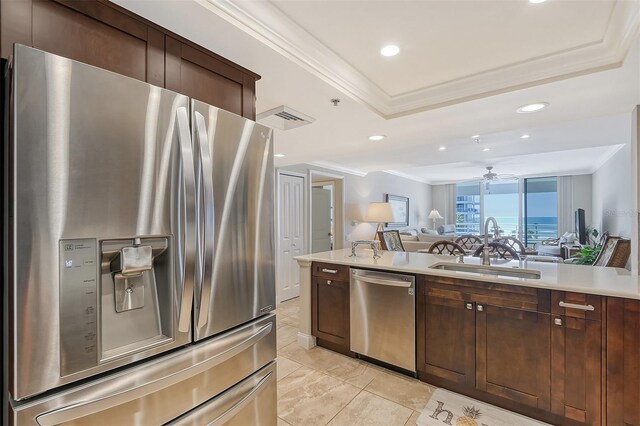 kitchen with dark brown cabinets, stainless steel appliances, ornamental molding, and sink