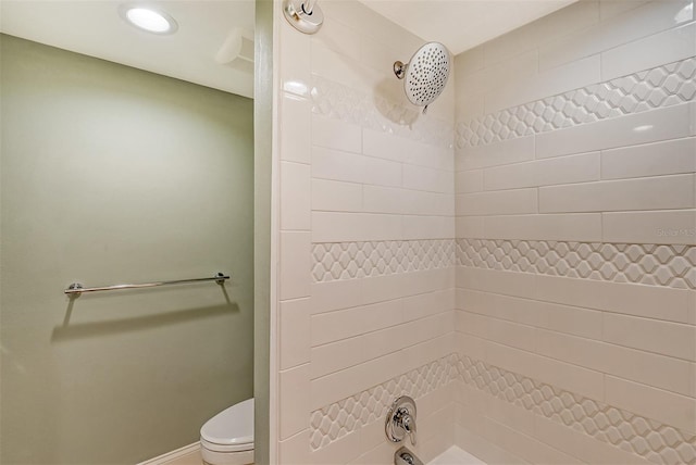 bathroom with a tile shower and toilet