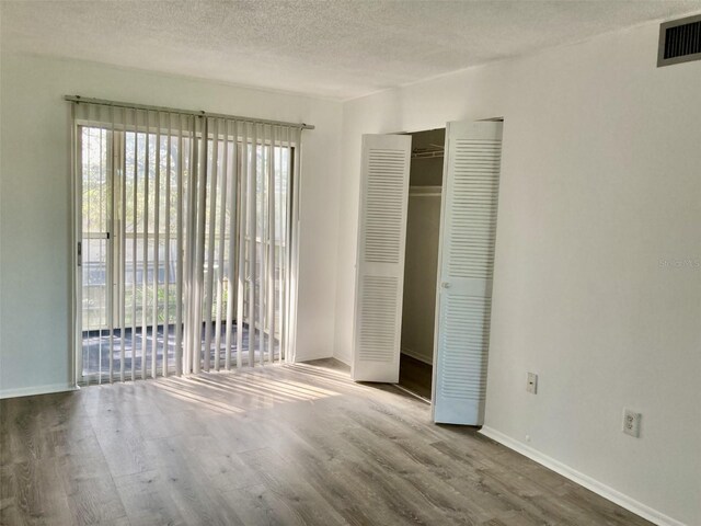 4480 Ironwood Cir Unit 218A, Bradenton, FL 34209 - unfurnished bedroom featuring multiple windows, wood finished floors, access to outside, a textured ceiling, and baseboards