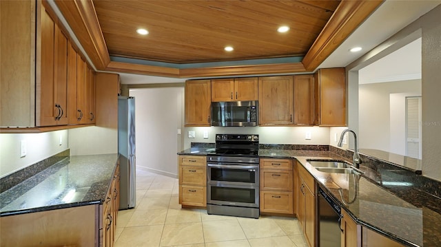 kitchen with sink, stainless steel appliances, a raised ceiling, dark stone counters, and light tile patterned floors