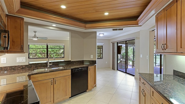 kitchen with a tray ceiling, sink, dark stone counters, and black dishwasher