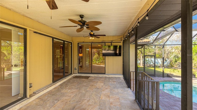 unfurnished sunroom featuring ceiling fan