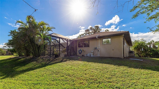 rear view of house with a lawn and a lanai