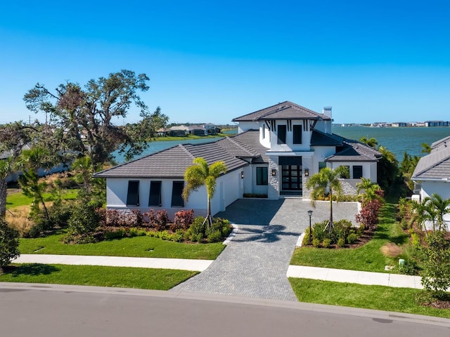 view of front of home with a garage, a water view, and a front yard