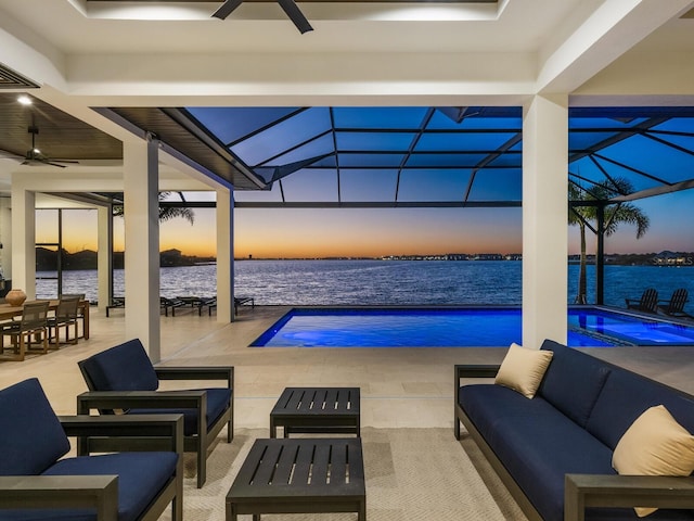 pool at dusk featuring an in ground hot tub, outdoor lounge area, a water view, glass enclosure, and a patio