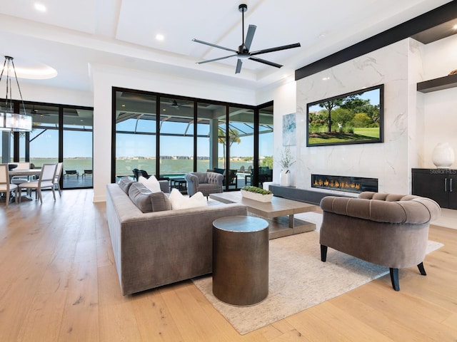 living room featuring ceiling fan, a fireplace, and light hardwood / wood-style floors