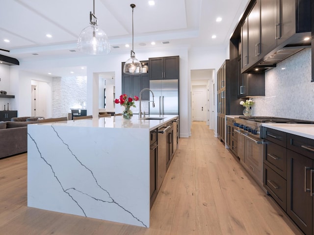 kitchen featuring a large island, light stone counters, backsplash, and light hardwood / wood-style flooring