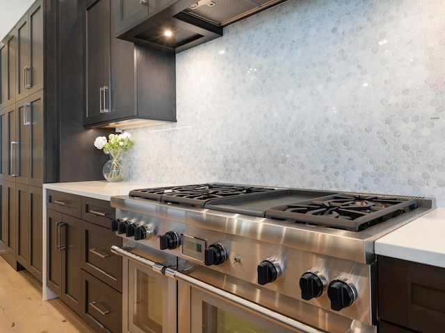 kitchen featuring backsplash, dark brown cabinetry, double oven range, and light hardwood / wood-style floors