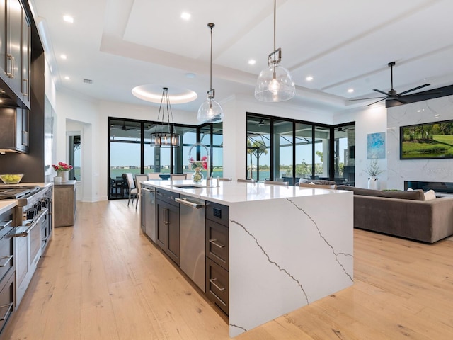 kitchen with pendant lighting, a large island, light stone counters, and a tray ceiling