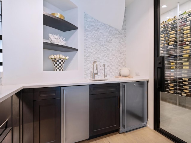 bar with backsplash, refrigerator, vaulted ceiling, sink, and light hardwood / wood-style floors