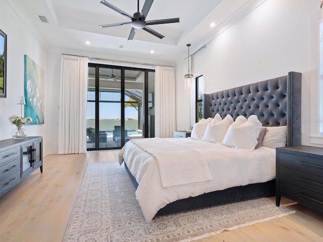 bedroom featuring access to exterior, a tray ceiling, ceiling fan, and light hardwood / wood-style floors