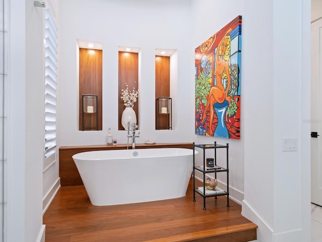 bathroom with hardwood / wood-style floors and a tub to relax in