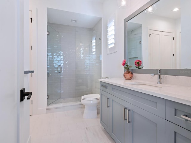 bathroom with vanity, toilet, and a shower with door