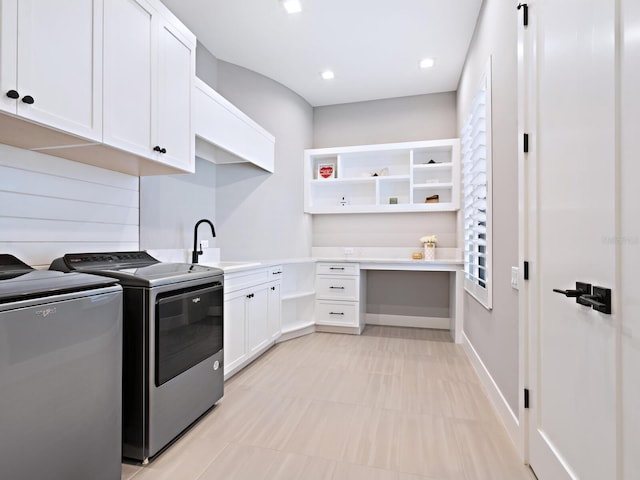 clothes washing area featuring washing machine and clothes dryer, cabinets, and sink