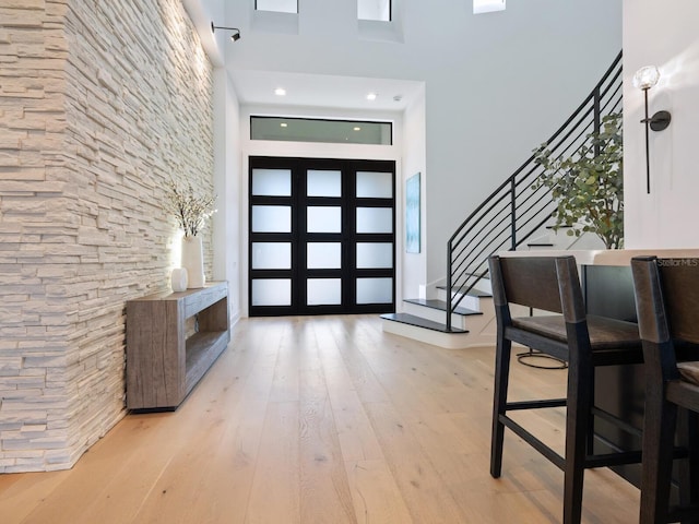 entrance foyer featuring light hardwood / wood-style flooring and a towering ceiling