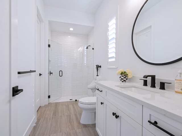 bathroom featuring a shower with door, vanity, and toilet