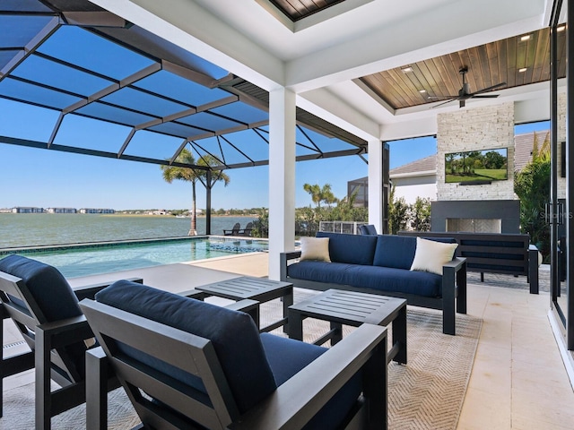 view of patio featuring an outdoor living space with a fireplace, ceiling fan, a water view, and a lanai