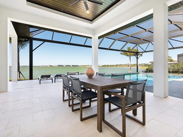 view of patio featuring a lanai, ceiling fan, and a water view