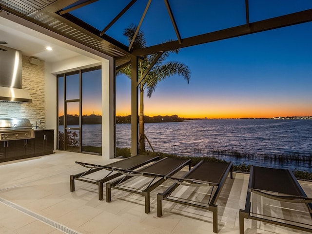 patio terrace at dusk with area for grilling and a water view