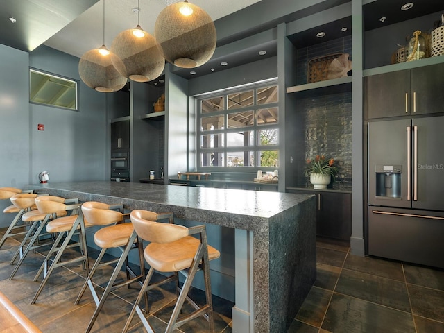 interior space with black oven, high end fridge, hanging light fixtures, and built in features