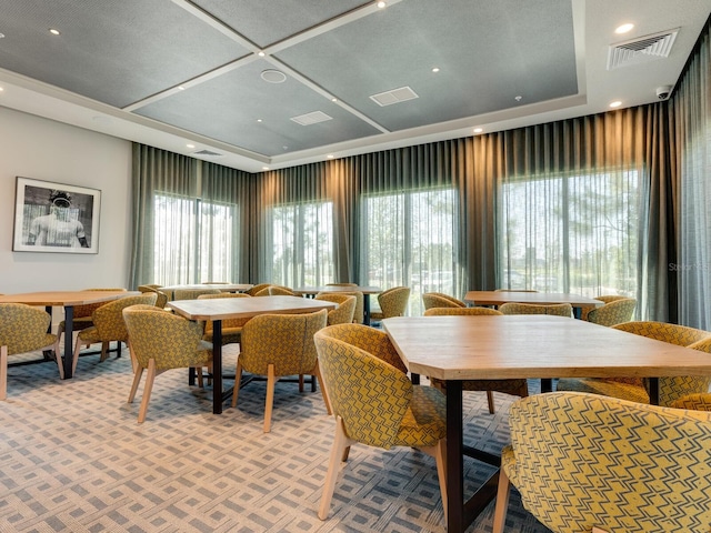 carpeted dining area featuring a raised ceiling and plenty of natural light