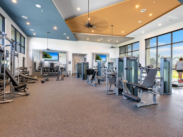 gym featuring ceiling fan and a towering ceiling