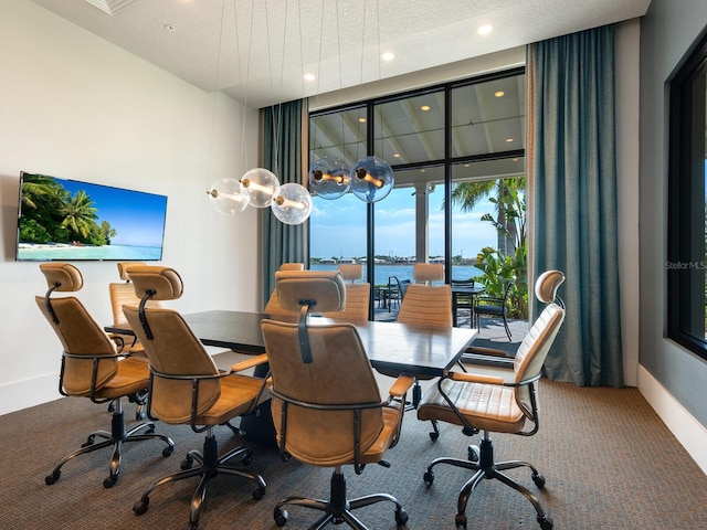 carpeted dining room featuring expansive windows and a water view