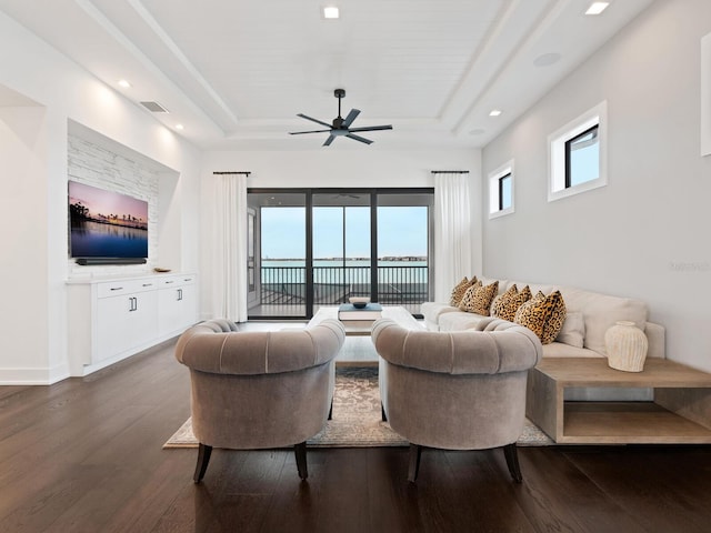 living room featuring a raised ceiling, ceiling fan, and dark hardwood / wood-style floors