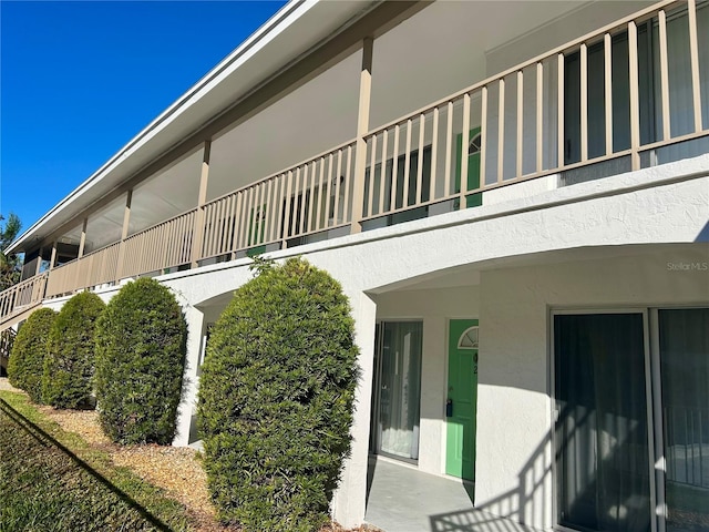 view of side of home featuring a balcony and stucco siding